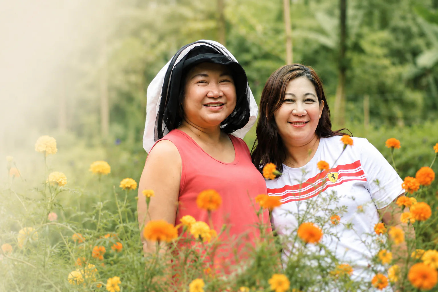 Two women from the Milea family smiling together in a flower garden